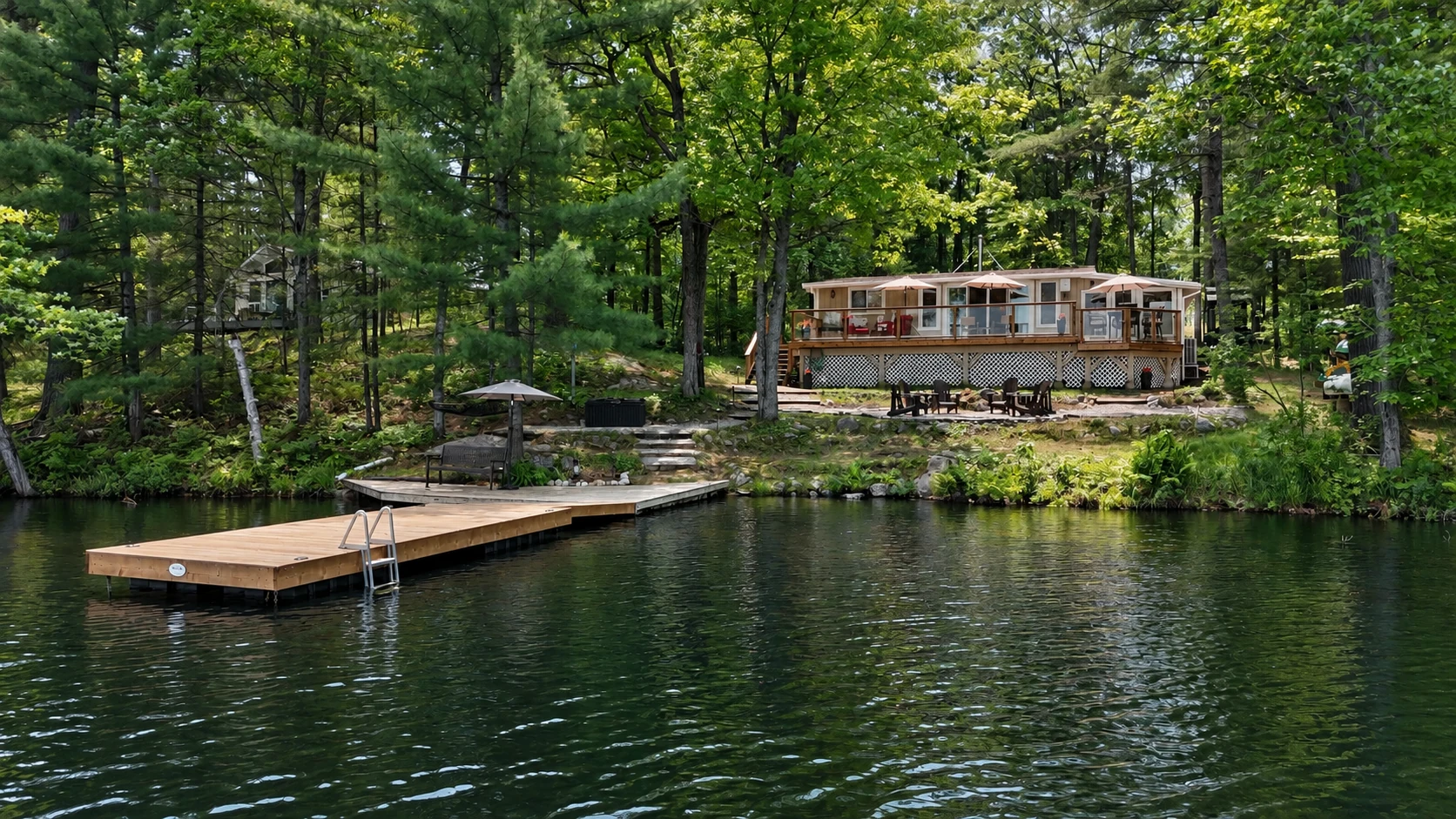 Waterfront cottage managed by SOCM in Ontario, featuring a private dock, spacious deck, lakeside seating, and surrounding forest.